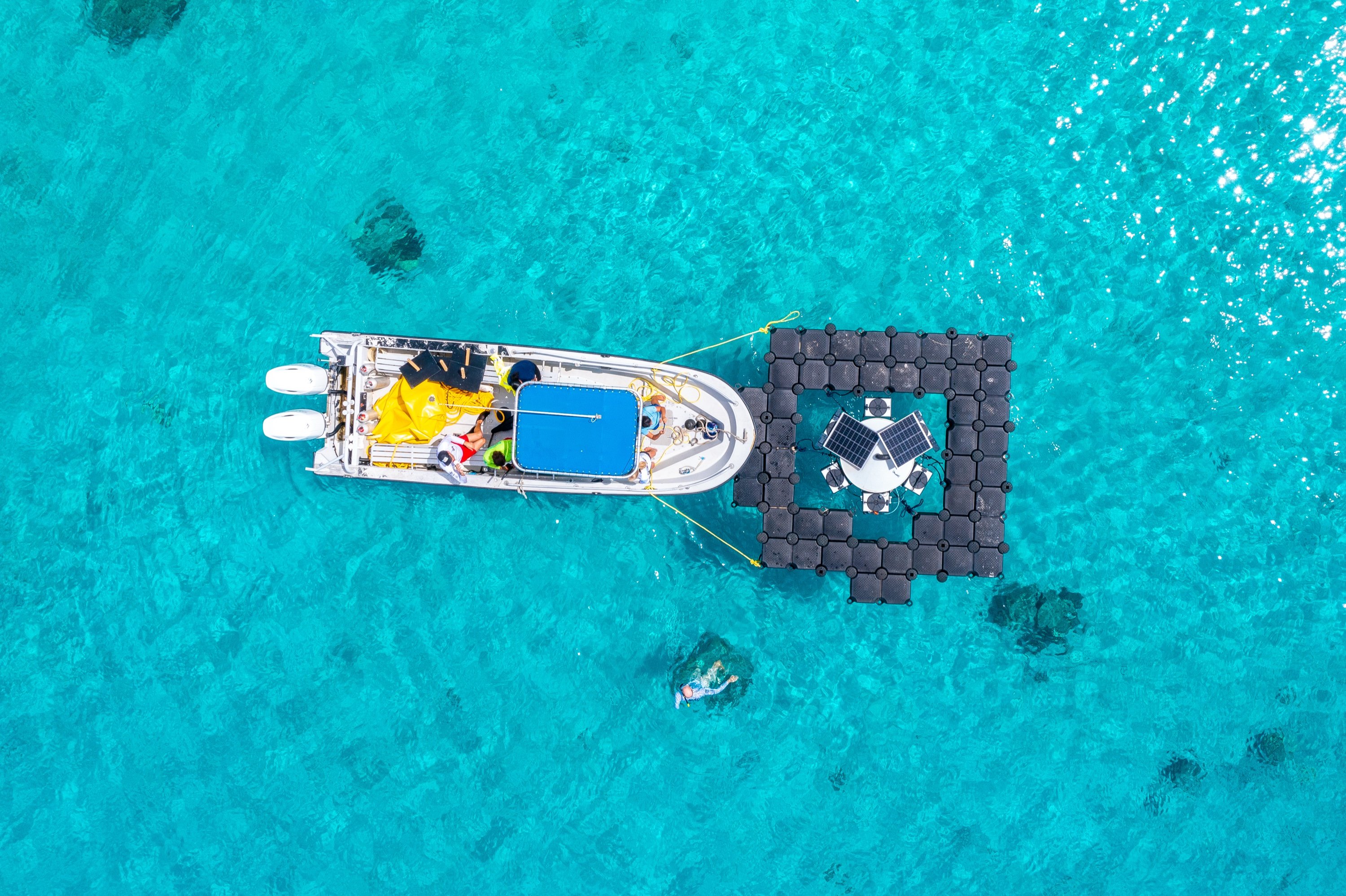 Luchtfoto van een drijvende RoffaReefs-kweekunit in turquoise water.