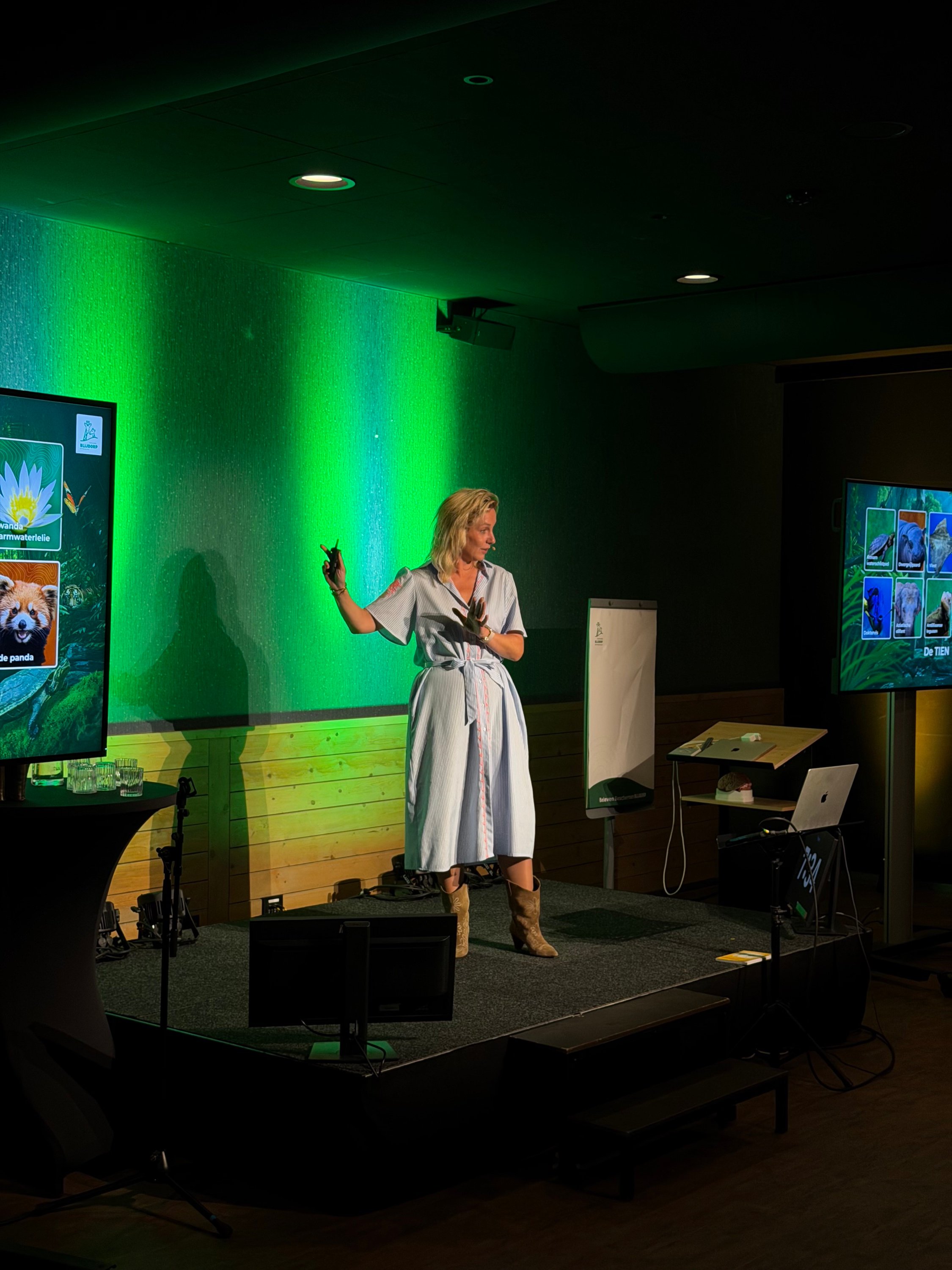Carolien Ottjes spreekt op het podium in groen licht.